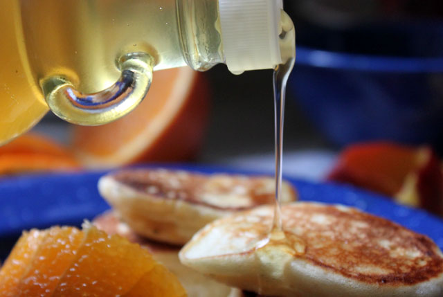 pouring ginger syrup on yeast raised pancakes